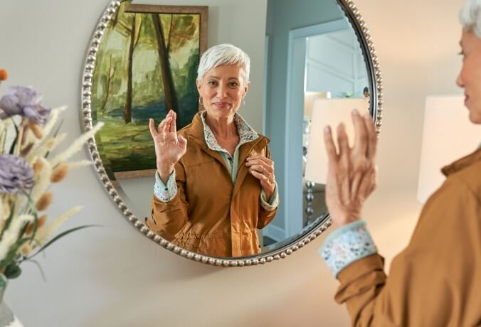 Image of a woman with her raised right hand with Dupuytren's contracture in a mirror